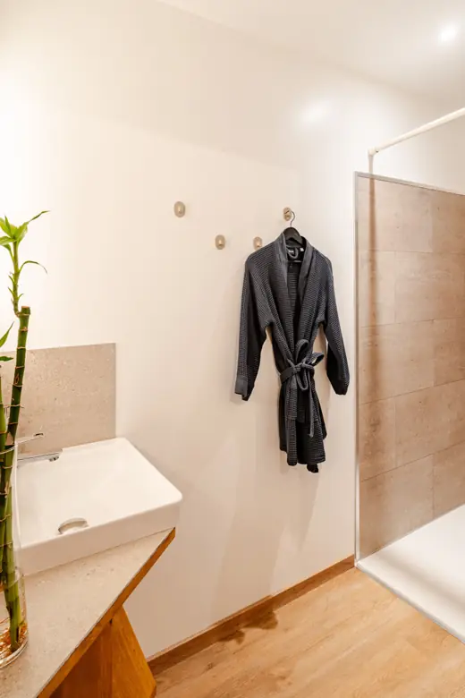 Salle d'eau avec douche à l'italienne et peignoirs